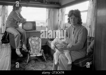 Gypsy-Großmutter und Baby-Enkelin, Innenraum eines Wohnwagens mit Fernseher. Appleby in Westmorland Gypsy Horse Fair Cumbria, England um den 1981 1980. Juni Stockfoto