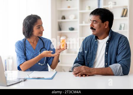 Lächelnde Indische Ärztin Zeigt Flasche Mit Pillen Einem Reiferen Männlichen Patienten Stockfoto