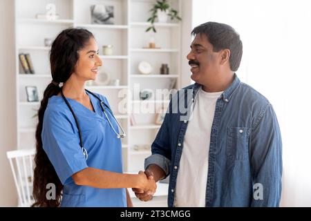 Dankbarer reifer indischer Mann, der mit Ärztin in der Klinik die Hand schüttelt Stockfoto