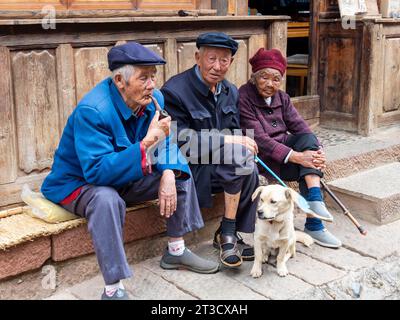 Alte Leute sitzen vor dem Haus, chinesische Rentner mit Hund, Shaxi, Yunnan, China Stockfoto