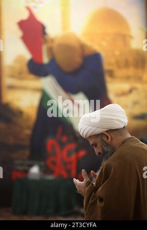 Teheran, Iran. Oktober 2023. Ein iranischer Geistlicher betet neben einem manipulierten Bild einer palästinensischen Frau während einer Gebetszeremonie, um Solidarität und Unterstützung für Gaza am heiligen Schrein von Imamzade Saleh im Norden Teherans zum Ausdruck zu bringen. (Kreditbild: © Rouzbeh Fouladi/ZUMA Press Wire) NUR REDAKTIONELLE VERWENDUNG! Nicht für kommerzielle ZWECKE! Stockfoto