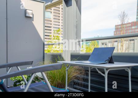 „Work from Home“-Konzept, Schreibtisch mit Laptop und Blumen auf der Terrasse Stockfoto