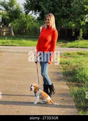 Frau, die mit ihrem süßen kleinen Hund an sonnigem Tag draußen läuft Stockfoto