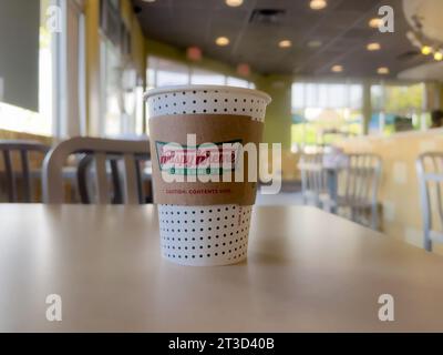Orange, CA, USA - 23. Oktober 2023: Eine Krispy Kreme Papierkaffeetasse mit einer Hülle auf einer Tischplatte. Stockfoto