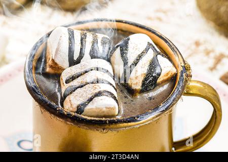 Heiße Schokolade mit Marschmalchen, Dampf oder Rauch, hausgemachtes Weihnachtsgetränk, mit mehreren Lebkuchenmännern auf dem Tisch Stockfoto