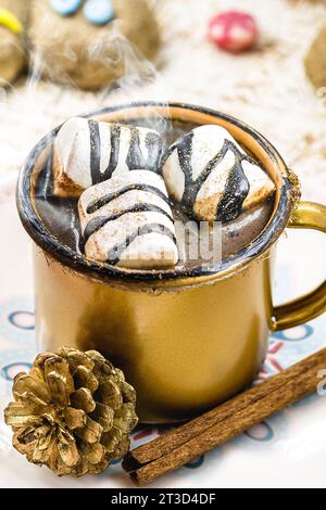 Heiße Schokolade mit Marschmalchen, Dampf oder Rauch, hausgemachtes Weihnachtsgetränk, mit mehreren Lebkuchenmännern auf dem Tisch Stockfoto