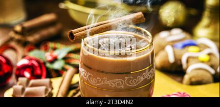 Heiße Schokolade mit Dampf oder Rauch, Weihnachtsgetränk, mit Lebkuchenmann im Hintergrund, Weihnachtsdessert Stockfoto