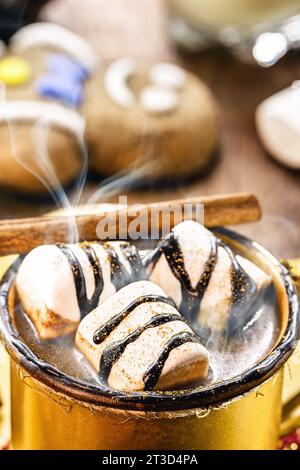 Heiße Schokolade mit Marschmalchen, Dampf oder Rauch, hausgemachtes Weihnachtsgetränk, mit Lebkuchenmann im Hintergrund Stockfoto