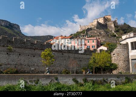 Das mittelalterliche Dorf mit den zinnenförmigen Mauern und Forte San Giovanni auf dem Hügel im Hintergrund, Finalborgo, Finale Ligure, Savona, Ligurien Italien Stockfoto