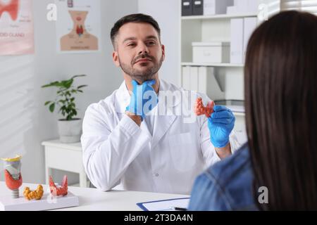 Endokrinologe zeigt Schilddrüsenmodell dem Patienten am Tisch im Krankenhaus Stockfoto