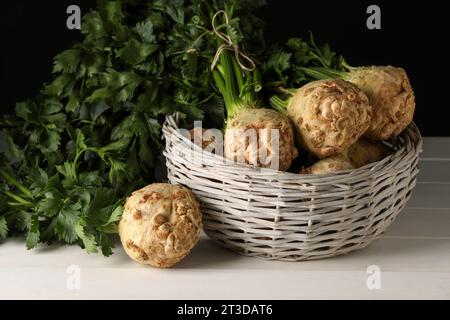 Fresh raw celery roots in wicker basket on white wooden table Stock Photo