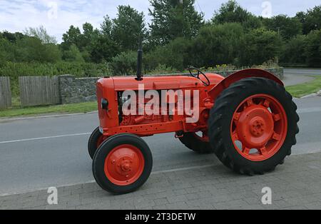 Alter Traktor auf der Straße in roter Farbe. Stockfoto