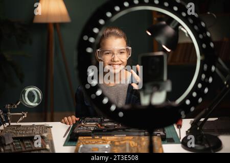 Mädchen Bloggerin mit kaputtem Laptop, Ringlampe und Smartphone Streaming in der Heimwerkstatt. Bloggen, Technologie und Menschen Stockfoto