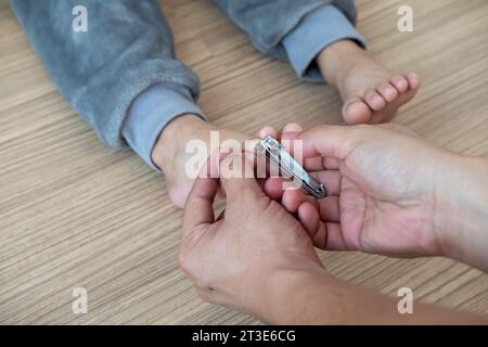 Die Hände einer Mutter, die ihrem Kind die Zehennägel schneidet Stockfoto