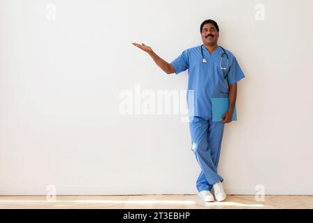 Porträt Eines Männlichen Indischen Arztes In Uniform, Der Auf Den Kopierraum Zeigt Stockfoto
