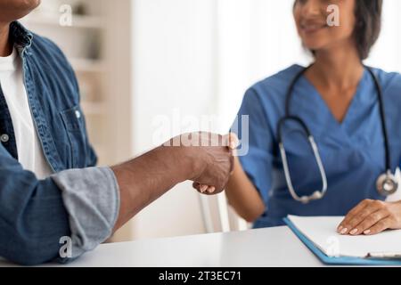 Medizinische Dienstleistungen. Arzt Frau Und Männlicher Patient Handschütteln Während Des Treffens In Der Klinik Stockfoto