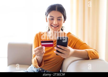 Mobile Zahlungen. Schöne Indische Frau, Die Zu Hause Smartphone Und Kreditkarte Benutzt Stockfoto
