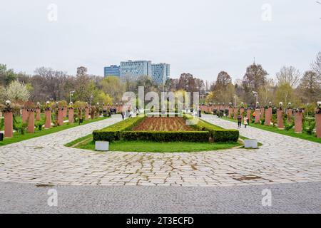 Bukarest, Rumänien - 17. April 2021: Landschaft mit Gras und großen alten grünen Bäumen zum wolkigen blauen Himmel im König Michael I Park (Herastrau), in einem Su Stockfoto