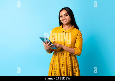 Indische Frau im Kleid, vertieft in E-Learning auf Tablet, Studio Stockfoto