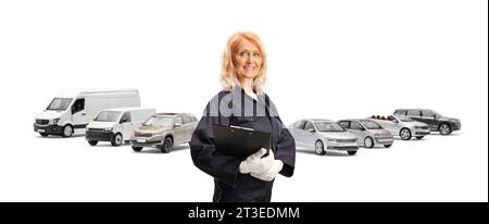 Eine Mechanikerin, die ein Klemmbrett hält und vor geparkten Fahrzeugen posiert Stockfoto