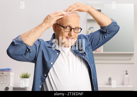 Reifer Mann im Badezimmer, der seine Haare überprüft Stockfoto