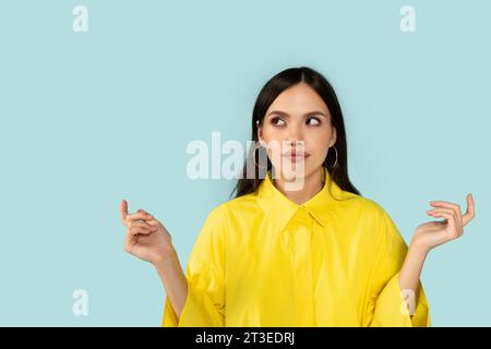 Unsichere junge Frau, die auf Kopierraum und Gesten blickt Stockfoto