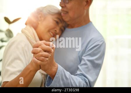 Foto von älteren Ehepaaren, die im Wohnzimmer tanzen und sich mit Liebe anschauen Stockfoto