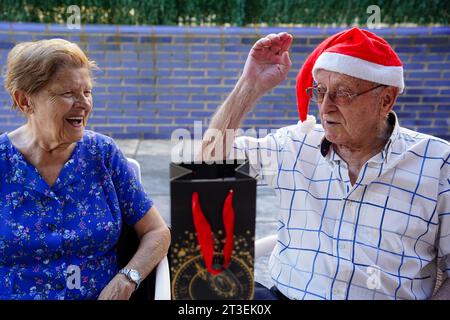 Ältere Ehe mit einem weihnachtsgeschenk mit einem weihnachtsmann-Hut. Alter Lebensstil im Weihnachtsalter Stockfoto
