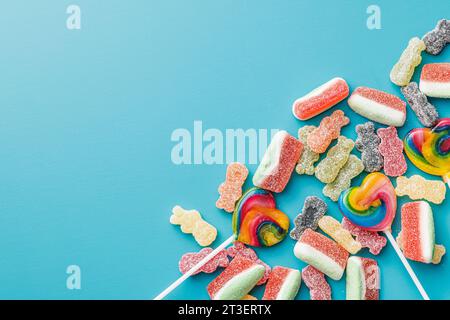 Süße Gelee-Bonbons und Lutscher auf blauem Hintergrund. Draufsicht. Stockfoto