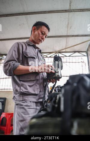 (231025) – HAIKOU, 25. Oktober 2023 (Xinhua) – Li Wenyong überprüft eine Infrarotkamera zu Hause im Autonomen County Baisha Li, südchinesische Provinz Hainan, 18. Oktober 2023. Li Wenyong ist ein Waldläufer im Hainan Tropical Rainforest National Park in der südchinesischen Inselprovinz. Er lebt im Dorf Miao in der Gemeinde Qingsong, die der Gerichtsbarkeit des Autonomen Bezirks Baisha Li untersteht, und dem nächstgelegenen Dorf in der Gegend von Bawangling. Das ist das Herz des Hainan Gibbon Country. Die Schwarzhaubenaffen sind nur in Hainan zu finden, und da sie nur selten Fuß auf den Boden setzen, nur in Regen Stockfoto