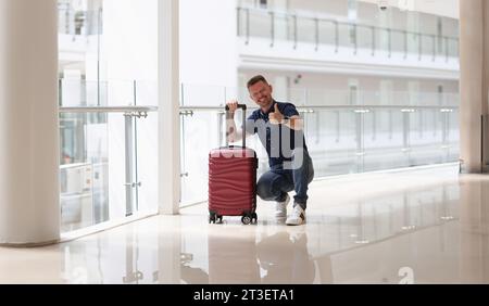 Mann mit Koffern, der im Hotelkorridor eine gute Geste zeigte Stockfoto