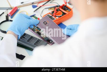 Meister öffnet die hintere Abdeckung des Mobiltelefons in der Nähe der Werkstatt Stockfoto