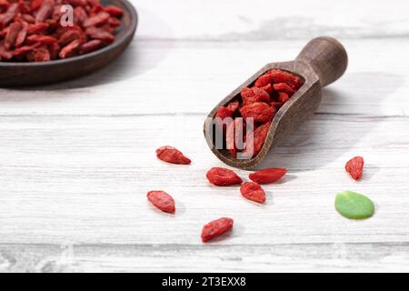 Getrocknete Goji-Beeren auf Holzlöffel und Holzteller auf weißem Hintergrund. Stockfoto