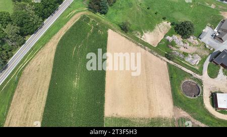 Ein Luftblick am späten Nachmittag auf Ackerland, Maisfelder, abgeerntete Felder, Silos, Barns und Rural Road, Sommertag Stockfoto