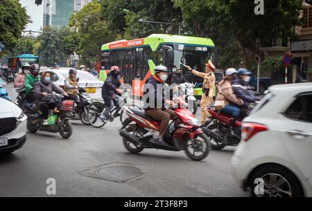 Ein Verkehrspolizist schwenkt mit seinem Stab, während er versucht, Ordnung an einer chaotischen Kreuzung in Hanoi, Vietnam, zu bringen. Stockfoto