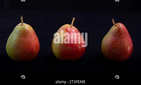 Drei leuchtende forelle Birnen hintereinander vor schwarzem Hintergrund. Stockfoto