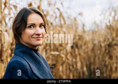 Porträt einer selbstbewusst lächelnden jungen kurzhaarigen Frau im Herbst inmitten eines Maisfeldes Stockfoto