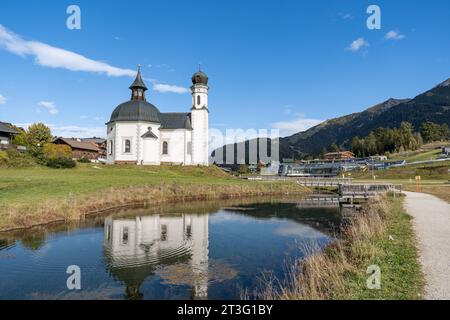 19.10.2023/Seefeld in Tirol, Österreich/Bild: Seekirche heiliges Kreuz, Seekirchl, Heiligkreuzkirche/vorne: Raabach, kleiner Bach/re.: Kongresszentrum Seefeld, Olympia Kongress, Olympiakongresszentrum, Olympia Sport- und Kongresszentrum, Olympiabad Seefeld/im Hintergrund re.: Skigebiet Rosshütte im Herbst *** 19 10 2023 Seefeld in Tirol, Österreich Bild Seekirchl, Heiligkreuzkirche vor Raabach, kleiner Bach Re Kongresszentrum Seefeld, Olympia Kongresszentrum, Olympia Sport- und Kongresszentrum Olympia, Olympiabad Seefeld im Hintergrund Re Ski A Stockfoto