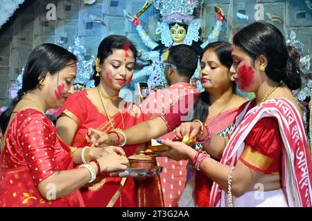 Frauen beschmieren sich fröhlich mit Vermillion im Rahmen der üppigen Durga Puja Festivalfeiern in Nagaon, Assam, Indien. Stockfoto