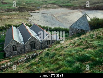 Kirche und freistehender W-Turm von St Winwaloe mit Blick auf Church Cove, Gunwalloe, Cornwall, England, Großbritannien. Der Glockenturm, der in die Klippe gebaut wurde, ist C13th. Stockfoto