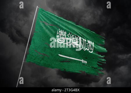 Saudi-Arabien zerrissene Flagge auf dunklem Himmel Hintergrund. Stockfoto