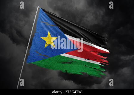 Südsudan zerrissene Flagge auf dunklem Himmel Hintergrund. Stockfoto