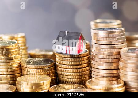 Die Immobilienkosten. Haus mit Münzstapeln. Stockfoto