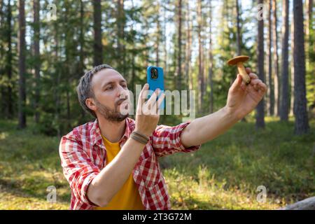 Ein Mann erfreut sich darüber, natürlichen Pilz zu finden, Fotos zu machen und in sozialen Netzwerken zu veröffentlichen Stockfoto