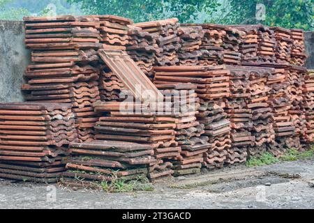 Stapel alter gebrauchter Dachziegel, weggeworfene rote Erddachziegel im Freien Stockfoto