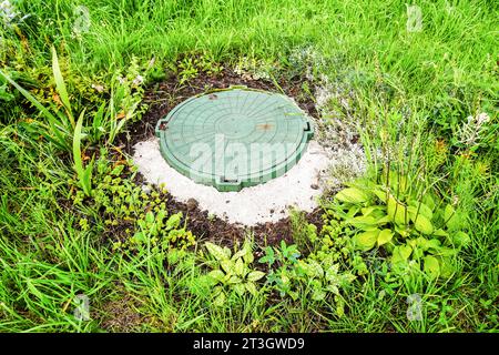 Überdachtes Kanalloch mit grüner Kunststoffabdeckung, Abwassersystem. Kanalisationsnetze für Landhäuser. Kanaldeckel für Sanitärkanalsysteme Stockfoto