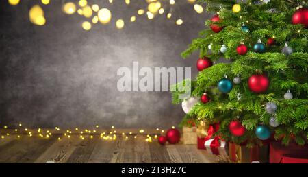 Herrlicher Weihnachtsbaum Nahaufnahme mit strukturierter grauer Wand als schöner Hintergrund mit Lichtern und Vignettierungen Stockfoto