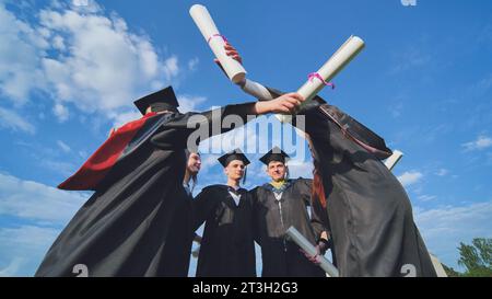Hochschulabsolventen umarmen sich in einem Kreis. Stockfoto
