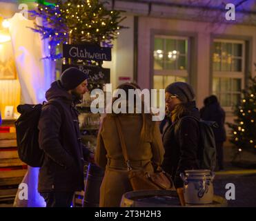 Heidelberg – 19. Dezember 2022: Jüngere Menschen im Gespräch mit Freunden auf dem Weihnachtsmarkt im Winter Stockfoto