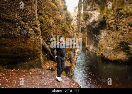 Europäischer Reisende, der den Blick auf den See unter bunten Bäumen beobachtet. Der europäische Mensch macht neue Entdeckungen im farbenfrohen Herbst in der Natur Stockfoto